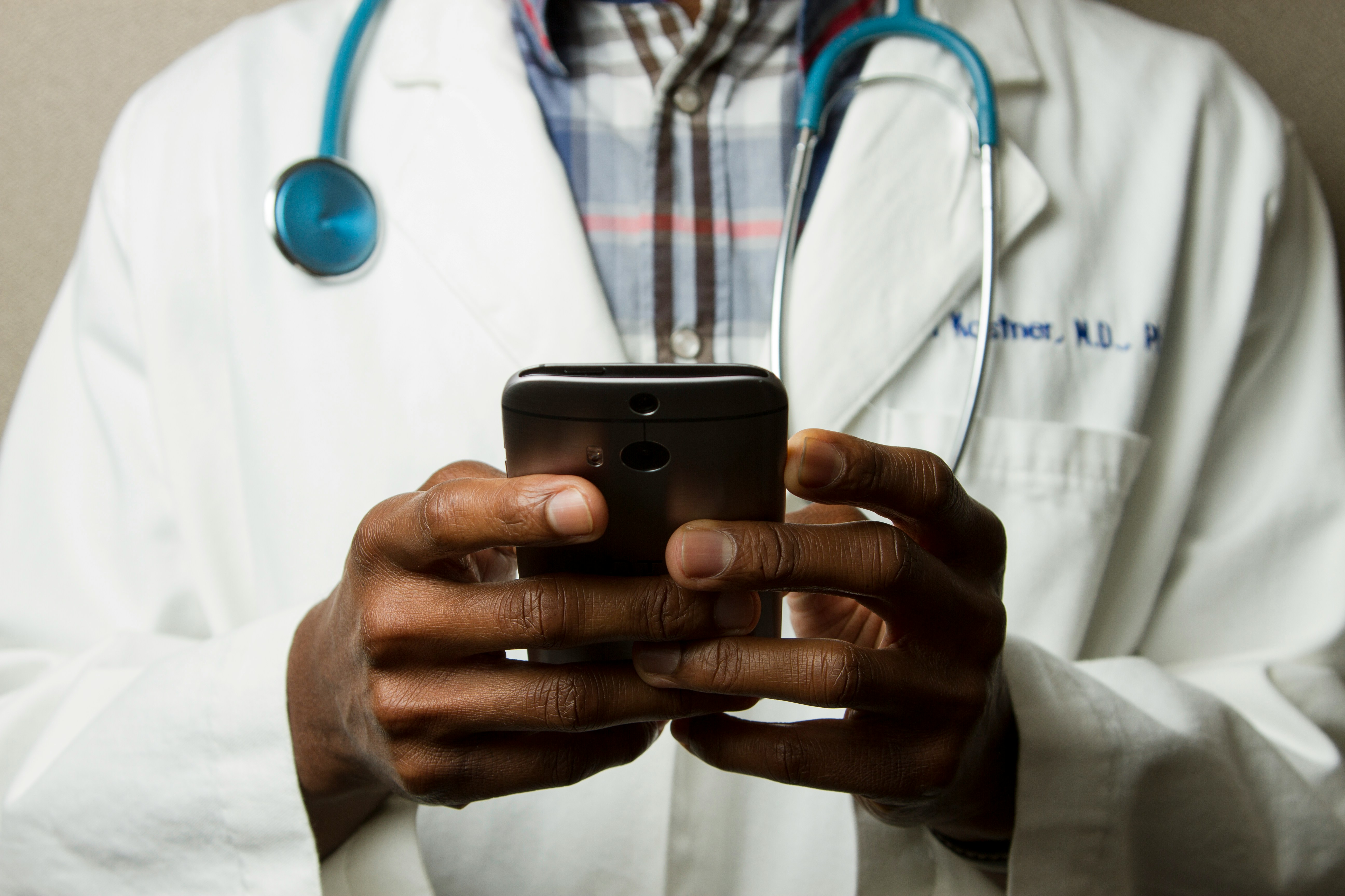 Arzt mit Smartphone – Symbolbild für Krankenkassen-Apps, die Kommunikation erleichtern, Papierkram reduzieren und digitale Gesundheitsservices bieten