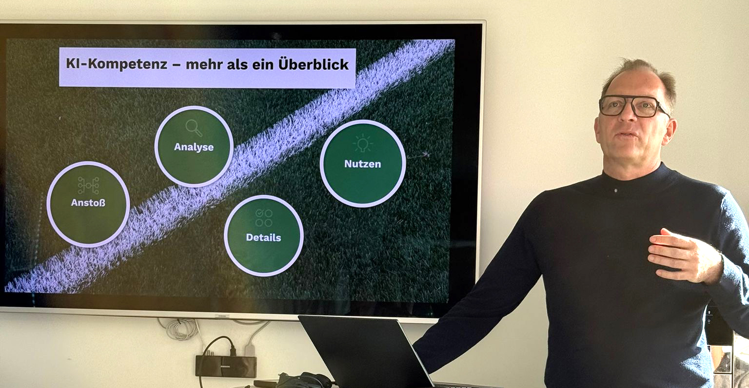 André Weinert steht neben einem Bildschirm. Auf dem Bildschirm zeigt eine Grafik, wie KI funktioniert.