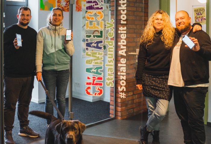 Vier Mitarbeiter des Chamäleon Stralsund e.V. stehen vor dem Eingang der Einrichtung. Auch ein Labrador schaut neugierig in die Kamera. 