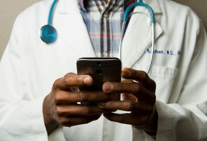 Arzt mit Smartphone – Symbolbild für Krankenkassen-Apps, die Kommunikation erleichtern, Papierkram reduzieren und digitale Gesundheitsservices bieten