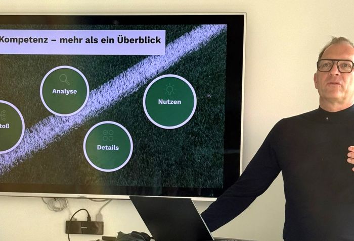 André Weinert steht neben einem Bildschirm. Auf dem Bildschirm zeigt eine Grafik, wie KI funktioniert.